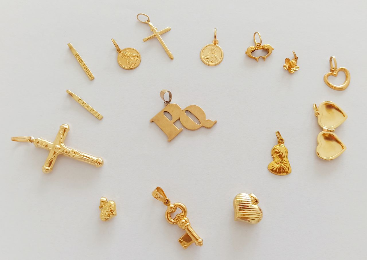 A variety of gold pendants and charms arranged artfully on a white surface, showcasing intricate designs.