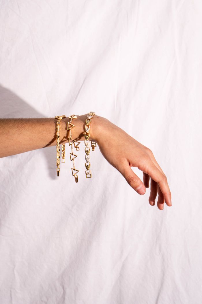 Close-up of a hand with gold bracelet against white background.